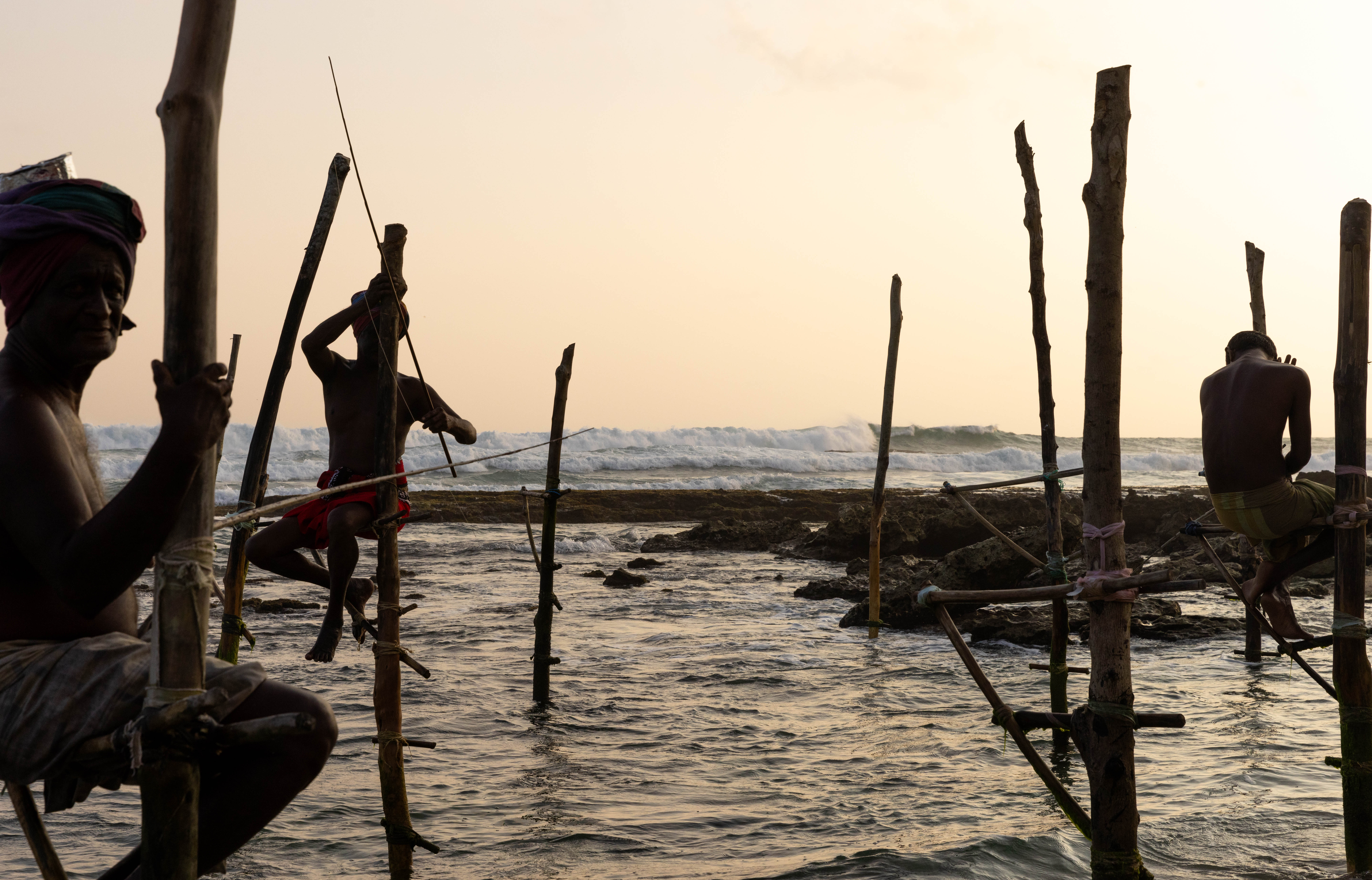 Traditional stilt fishermen sitting together above the ocean